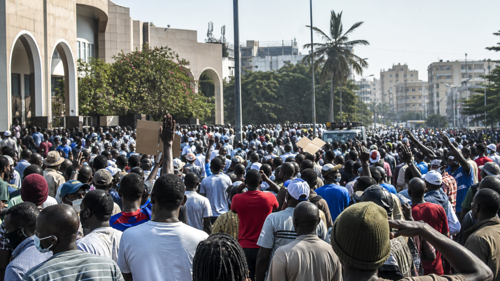 Illustration générée par IA pour l'article « Crise politique au Sénégal » : manifestation politique au Sénégal avec citoyens rassemblés dans une rue, débats animés et pancartes de protestation.